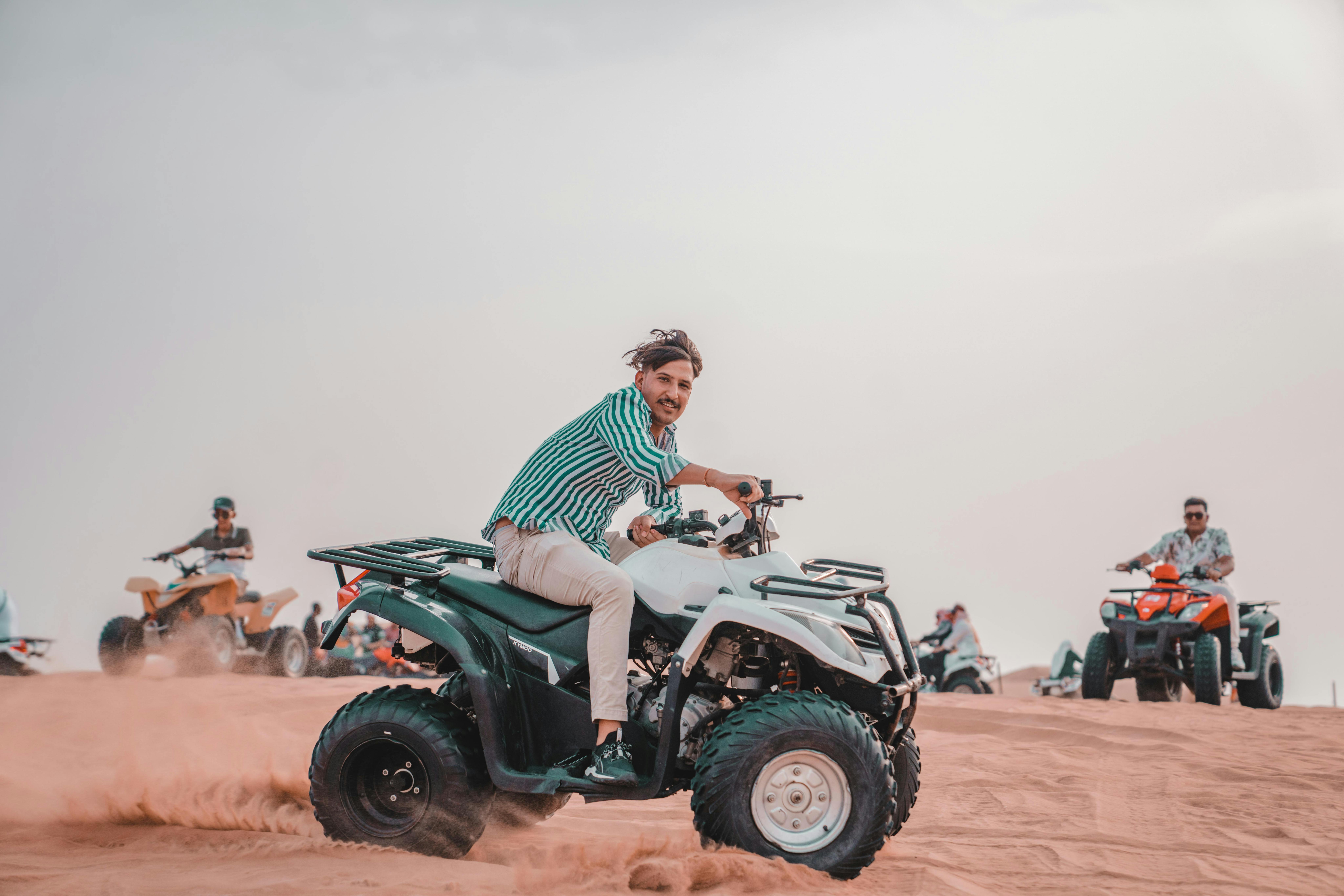 Three people on ATVs and buggy on beach
