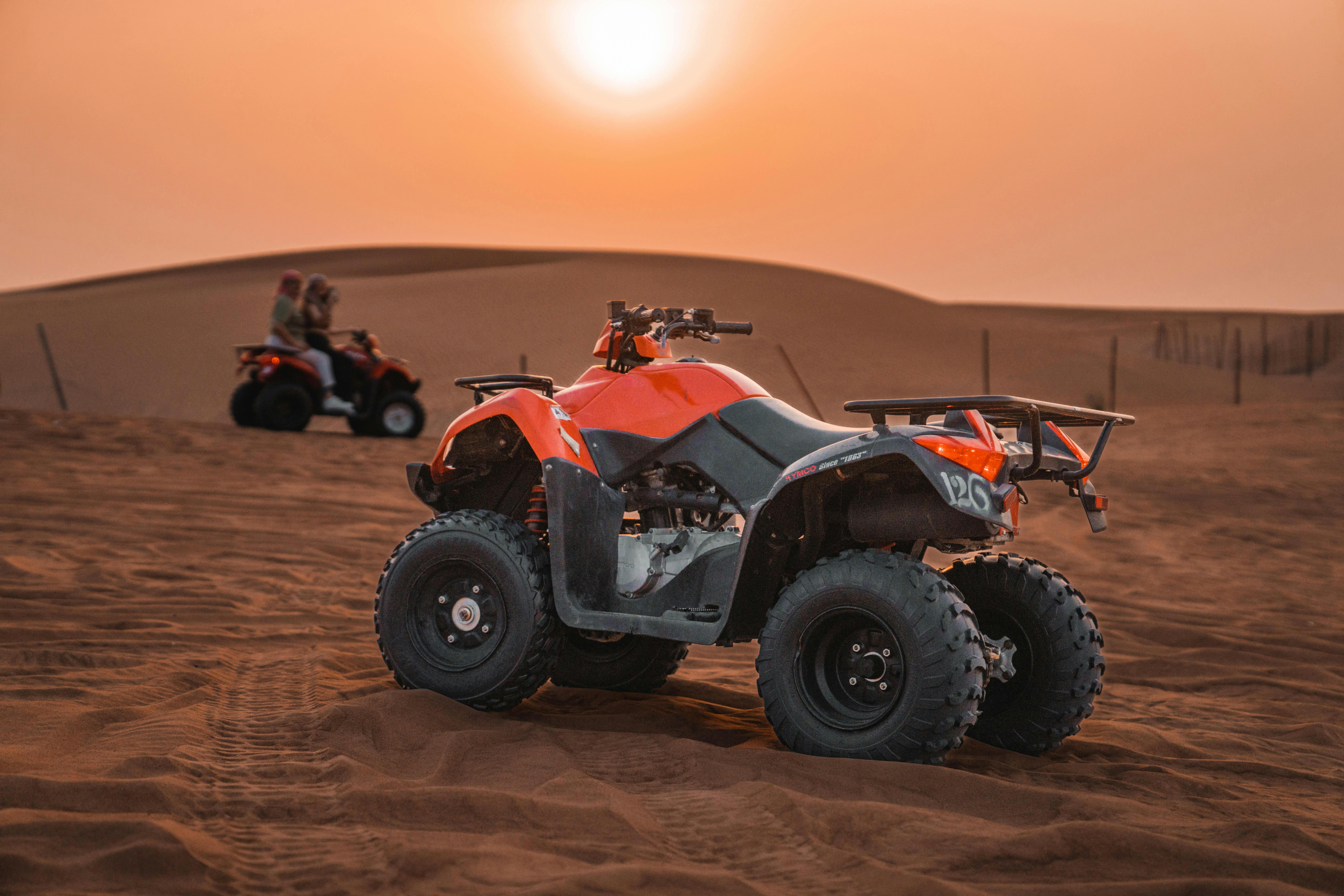 ATVs on sand dunes during sunset